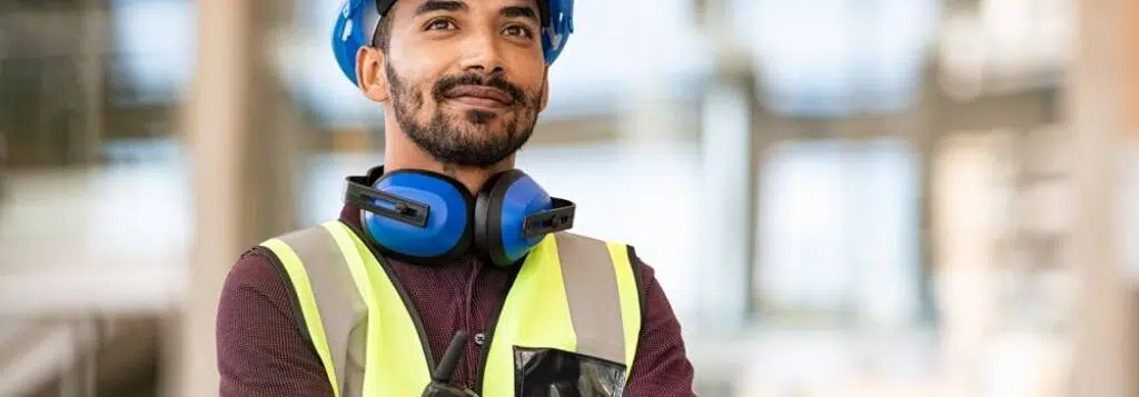 A construction site manager wears PPE while supervising his staff