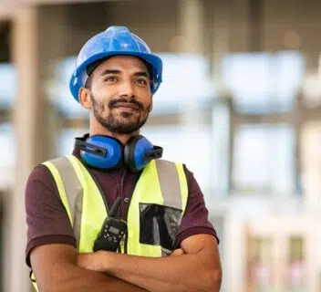 A construction site manager wears PPE while supervising his staff