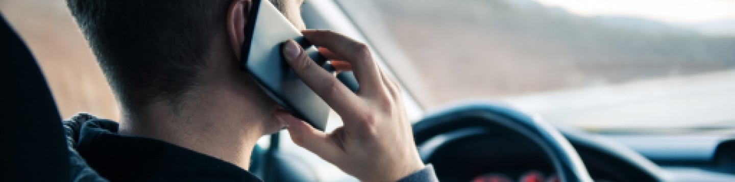 Image of man on phone while operating motor vehicle.