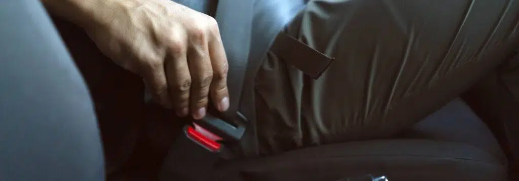 A man fastening his seatbelt in a car.