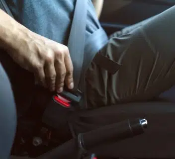 A man fastening his seatbelt in a car.